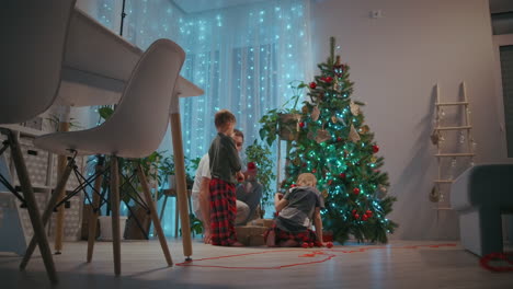 Father-and-two-boys-decorate-Christmas-tree-on-New-Year's-Eve-and-Christmas.-High-quality-4k-footage